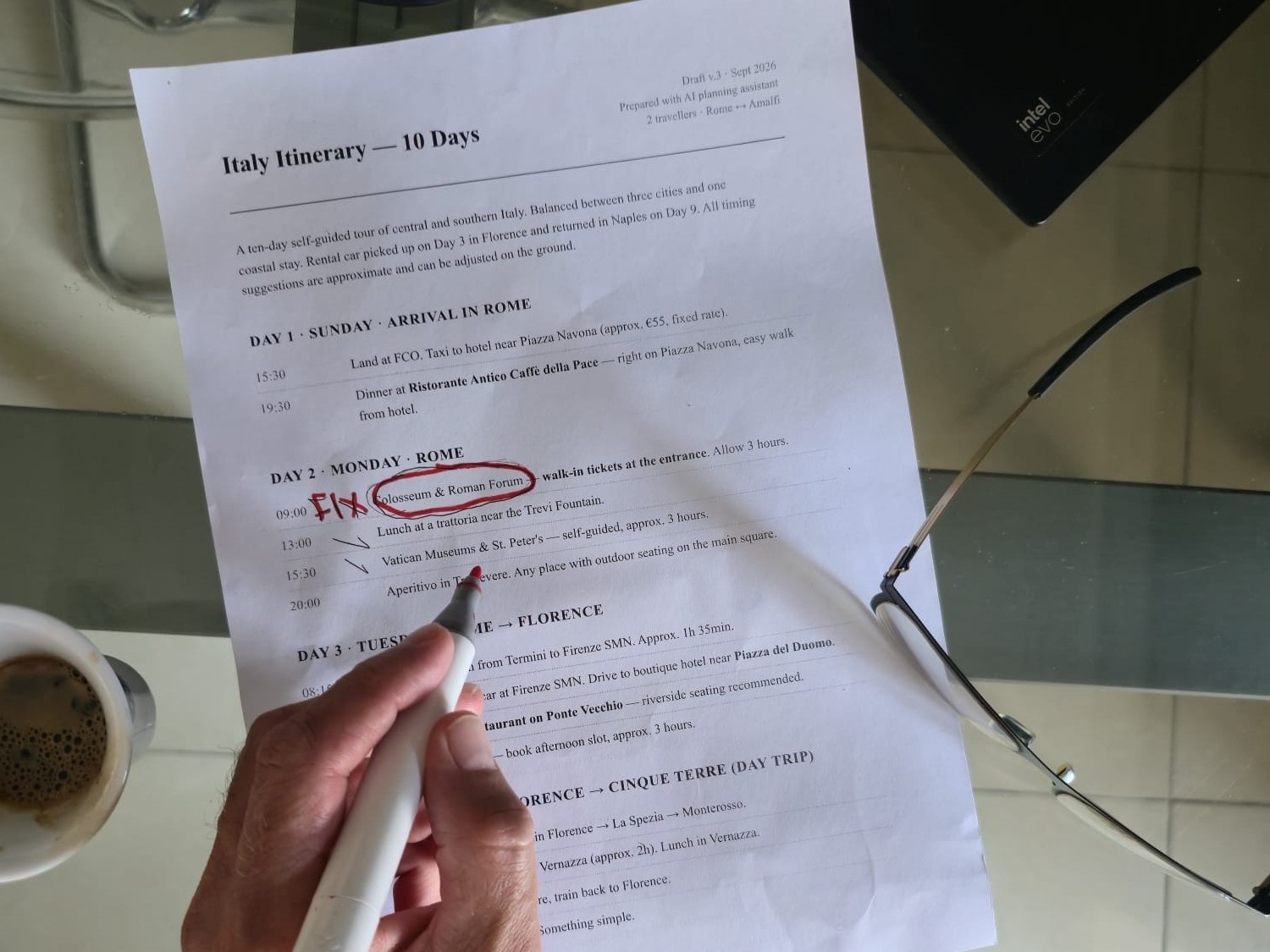 A printed Italy itinerary marked up in red pen by a human reviewer, next to a coffee cup and glasses